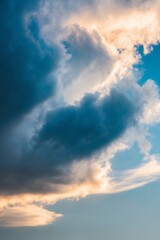 Obraz premium Dramatic blue clouds illuminated by sunlight during early evening sky.