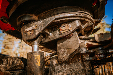 Close-up of a forestry harvester&rsquo;s hydraulic joint, showing worn, rugged metal parts and cables, highlighting heavy-duty machinery and engineering details..