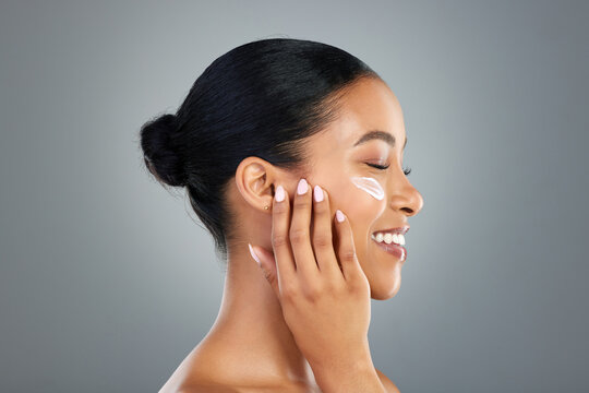 Woman, cream and skincare in studio profile with smile, test and results for beauty by background. Girl, person and model with cosmetics, makeup and moisturizer serum with touch for transformation