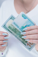 female hands holding Russian rubles and American dollar paper bills