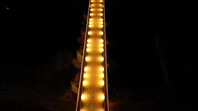 Aerial high angle footage of a 150 years old stone masonry bridge illuminated on a dark night. Drone shot of Master Kolyo Fitcheto's bridge at Byala village over the river of Yantra in Bulgaria.
