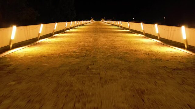 Aerial high angle footage of a 150 years old stone masonry bridge illuminated on a dark night. Drone shot of Master Kolyo Fitcheto's bridge at Byala village over the river of Yantra in Bulgaria.
