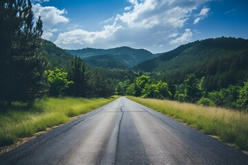 Naklejka premium Open road through green mountains under a blue sky