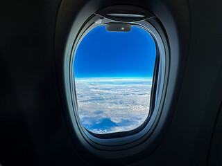 Blue sky seen through the window of a holiday jet at cruising altitude. Travel concept.