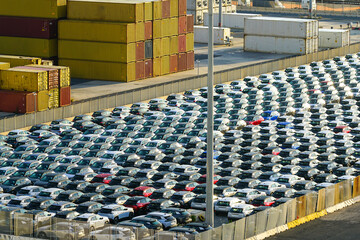 Industrial area of the port filled with many new cars and stacked cargo containers