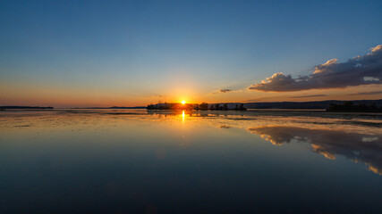 wide angle view of sunset over a lake with clouds reflected in the water