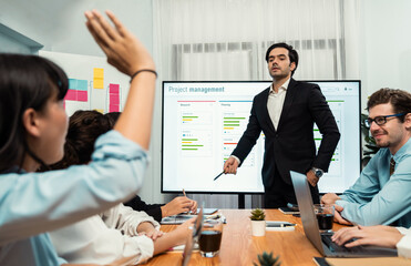 Corporate employee raise hand ask question during project meeting, businessman or manager explaining business task planning schedule with timeline software show on TV screen. Habiliment