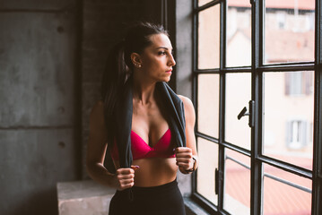 Image of a fit young woman training and working out in a industrial styled old gym. Female athlete using gym equipment as ropes, barbells and weights.