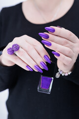 Female hand with white skin, long nails and purple blue manicure