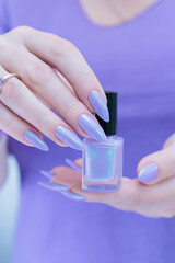 Female hand with long nails and a lilac blue nail polish