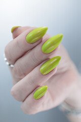 Female hand with long nails and yellow green manicure