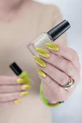 Female hand with long nails and a yellow green nail polish