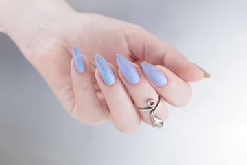 Woman hand with long nails manicure and light lilac and blue nail polish