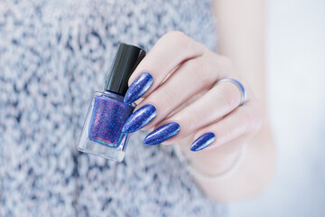 Female hand with long nails and a blue and purple color nail polish