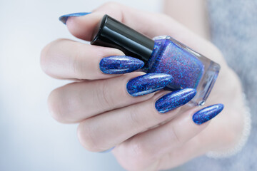 Female hand with long nails and a blue and purple color nail polish