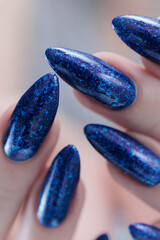 Woman's beautiful hand with long nails and bright blue purple manicure