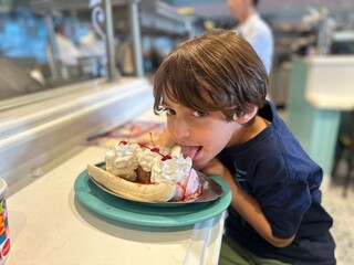 boy eating a banana split having fun in a diner 