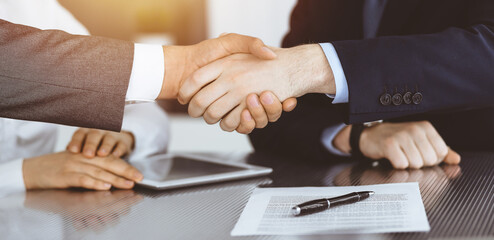 Handshake as successful negotiation ending, close-up. Unknown business people shaking hands after contract signing in modern office