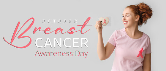 Young woman with ribbon and cookie on light background. Breast cancer awareness concept