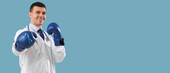 Male urologist in boxing gloves with blue ribbon on color background. Prostate cancer awareness...