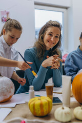 Fototapeta premium Children and adults painting pumpkins for Halloween, enjoying a fun and creative activity together.