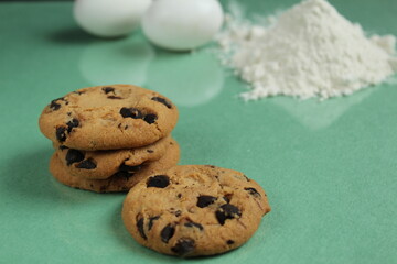 Cookies on a green background, flour and eggs are lying nearby. Visual cookie recipe