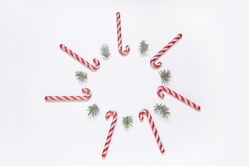 Frame made of Christmas tree branches and candy canes on white background