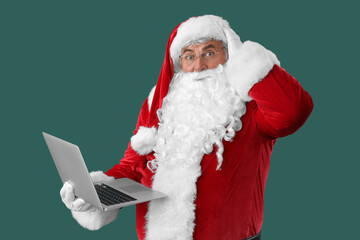 Shocked Santa Claus with laptop on green background