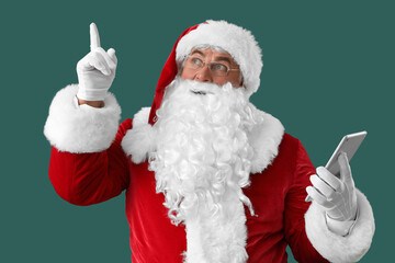 Santa Claus with tablet computer pointing at something on green background