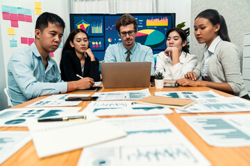 Diverse group of business analyst team analyzing financial data report. Finance data analysis chart and graph dashboard show on TV screen in meeting room for strategic marketing planning. Meticulous
