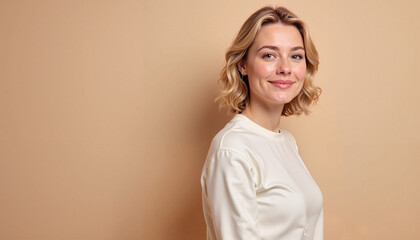 Fototapeta premium Smiling young woman with curly hair posing against a beige background for portrait photography, copy space