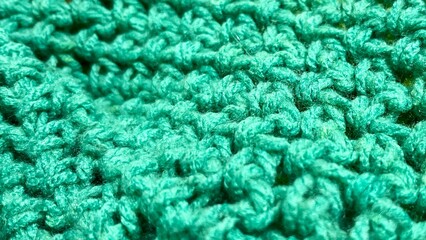 green wool thread crochet texture . gray background close . side view . copy space