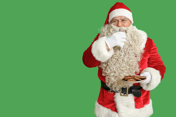 Santa Claus drinking milk with tasty cookies on green background