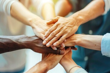 Fototapeta premium close-up shot of diverse friends from different races stacking their hands together, symbolizing unity and teamwork.