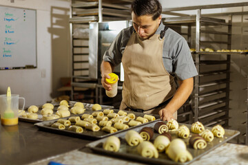 The Mexican baker carefully sprinkles sugar onto the pan dulce, creating a sweet and crunchy layer that will caramelize in the oven