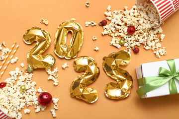 Figure 2024 made of golden air balloons with popcorn and Christmas decor on orange background