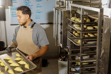 In the bakery, a Mexican baker meticulously organizes trays filled with pan dulce, preparing them...