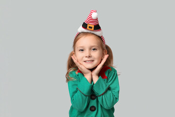 Cute little girl dressed as elf on grey background