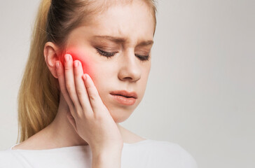 Young woman touching her cheek, having strong toothache and suffering from pain, empty space