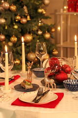 Festive table setting with burning candles and Christmas decorations at evening, closeup