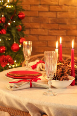 Dining table with Christmas setting and burning candles in room, closeup