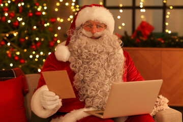 Santa Claus with laptop and letter at home on Christmas eve