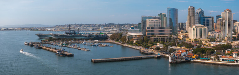Obraz premium Aerial view of San Diego, California, highlighting the USS Midway Museum, modern skyscrapers, and a bustling marina with boats and yachts.
