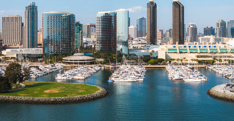Aerial view of San Diego, California, featuring a skyline of high rise buildings, a marina with boats, and the San Diego Convention Center's peaked roofs.