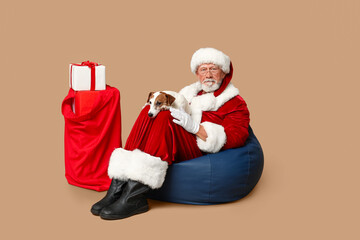 Santa Claus with cute Jack Russell Terrier dog and gifts on brown background