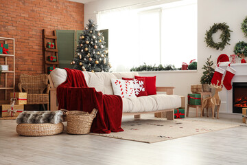 Interior of festive living room with cozy white sofa, fireplace and Christmas decorations