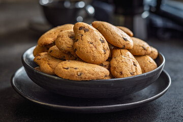 Biscotti frollini con gocce di cioccolato. Chocolate cookies on plate on black table.