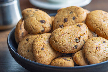 Biscotti frollini con gocce di cioccolato. Chocolate cookies on plate on wooden table.