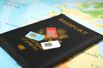 Modern SIM cards and passport on world map, closeup