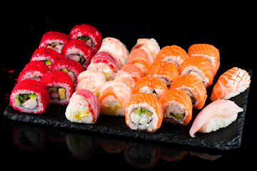 Set of japanese sushi rolls with tuna, salmon, shrimp, cucumber, avocado, sweet pepper, cream cheese, rice paper and red flying fish caviar.